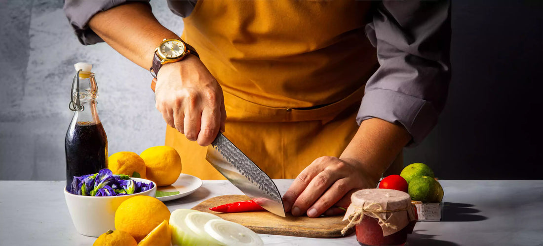 Un cuisinier se sert d'un couteau japonais pour couper un poivron rouge sur une planche en bois