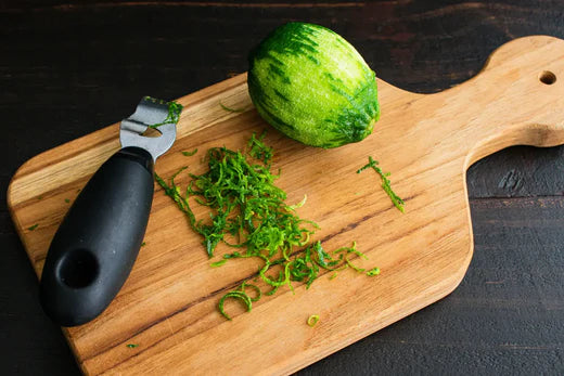 Zesteur sur un citron vert sur une planche en bois