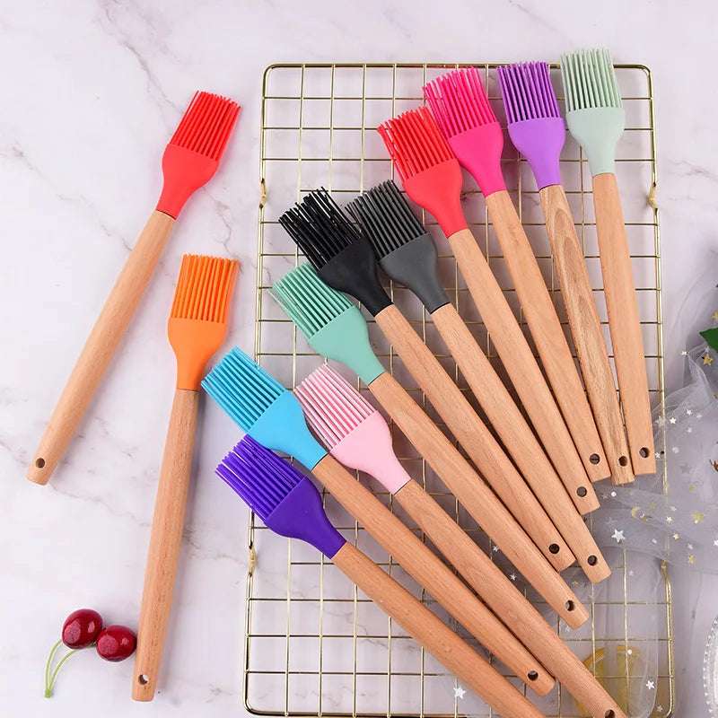 Ensemble de pinceaux colorés avec brosses en silicone et manches en bois, disposés sur une grille métallique.