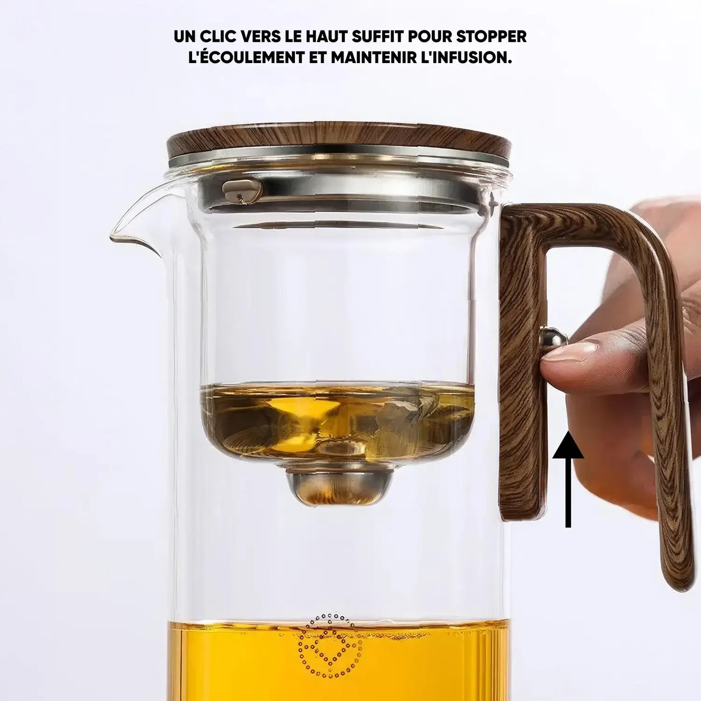 Théière en verre avec infuseur intégré, montrant une main actionnant le bouton sur la poignée pour stopper l'écoulement du thé.