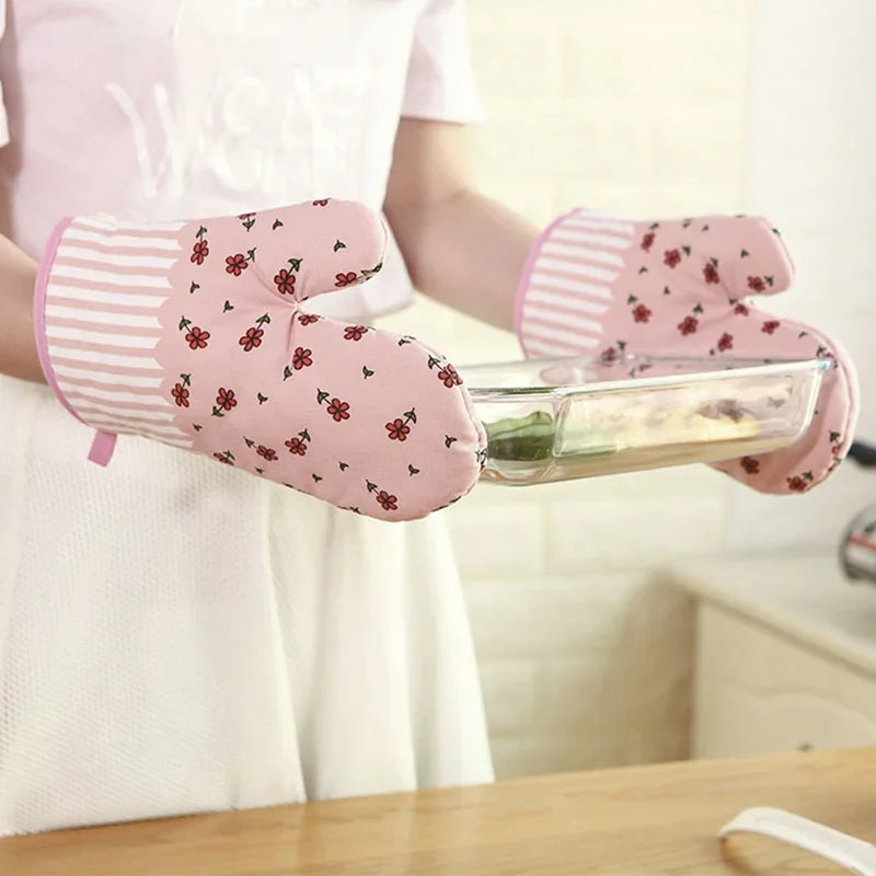 Femme utilisant des gants de cuisine roses à motif floral pour sortir un plat du four.
