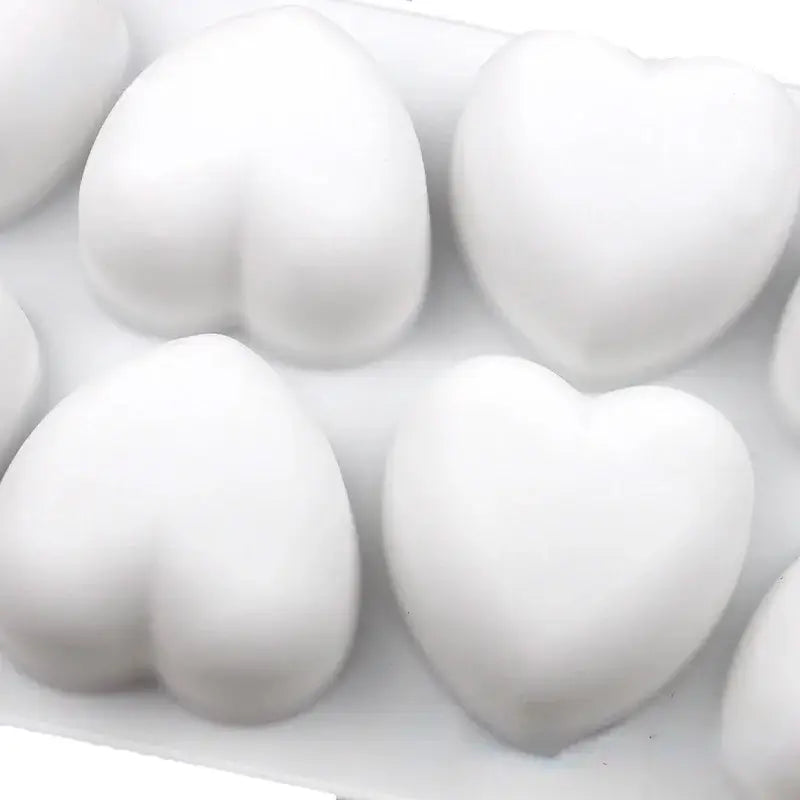 Un moule blanc avec des empreintes en forme de grands cœurs tridimensionnels.