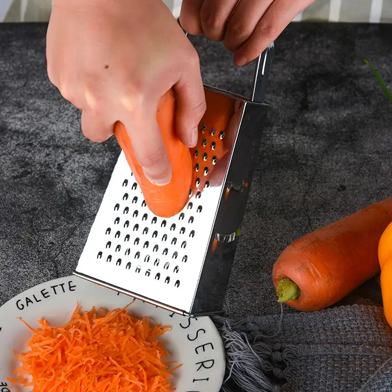 Une personne utilisant une râpe de cuisine en acier inoxydable pour râper une carotte orange au-dessus d'une assiette.